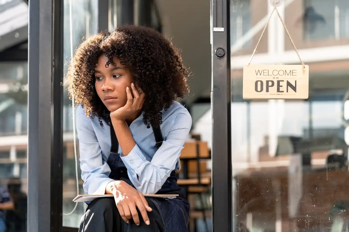 Worried businesswoman sits near open sign